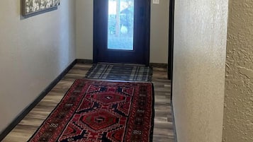 A hallway with a patterned rug, a door with a view, and a framed picture on the wall.