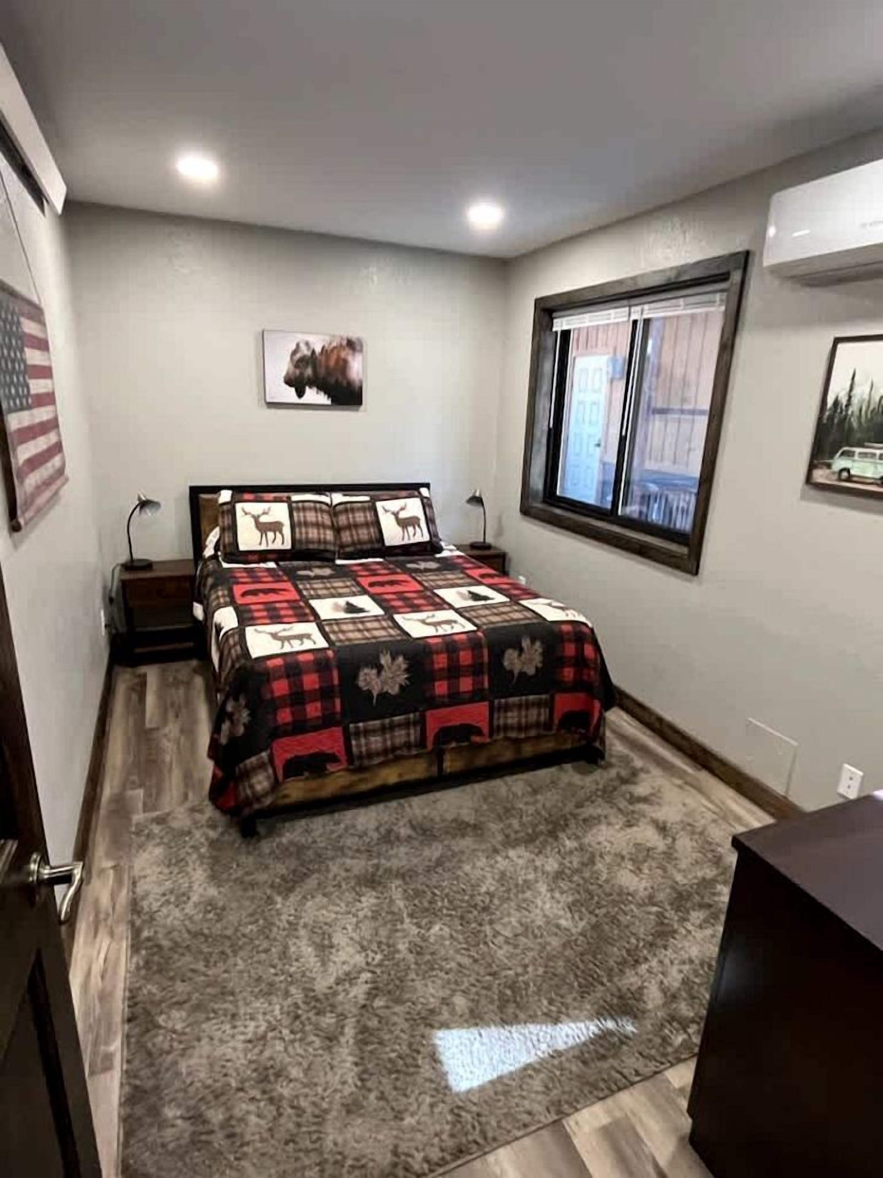 Ein Schlafzimmer mit Bett, Fenster, Teppich und einem Wandbild.