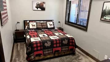 Ein Schlafzimmer mit Bett, Fenster, Teppich und einem Wandbild.