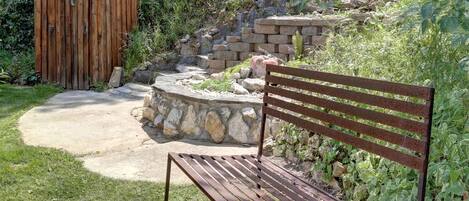 A wooden bench and a small wooden structure in a garden with a stone pathway and steps.