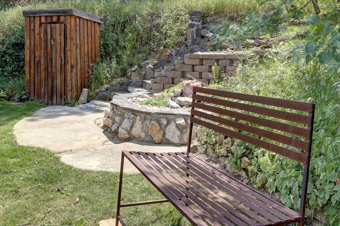 Eine hölzerne Bank und eine Steinmauer in einem Garten.