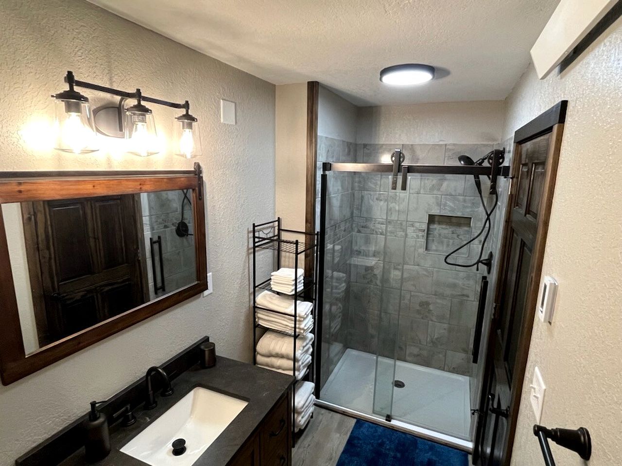 Ein Badezimmer mit Duschkabine aus Glas, Waschbecken mit Spiegel und Handtuchhalter.