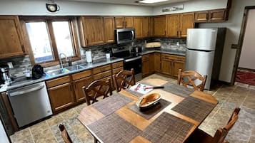 A kitchen with wooden cabinets, a stainless steel refrigerator, a microwave, and a dining table with placemats.