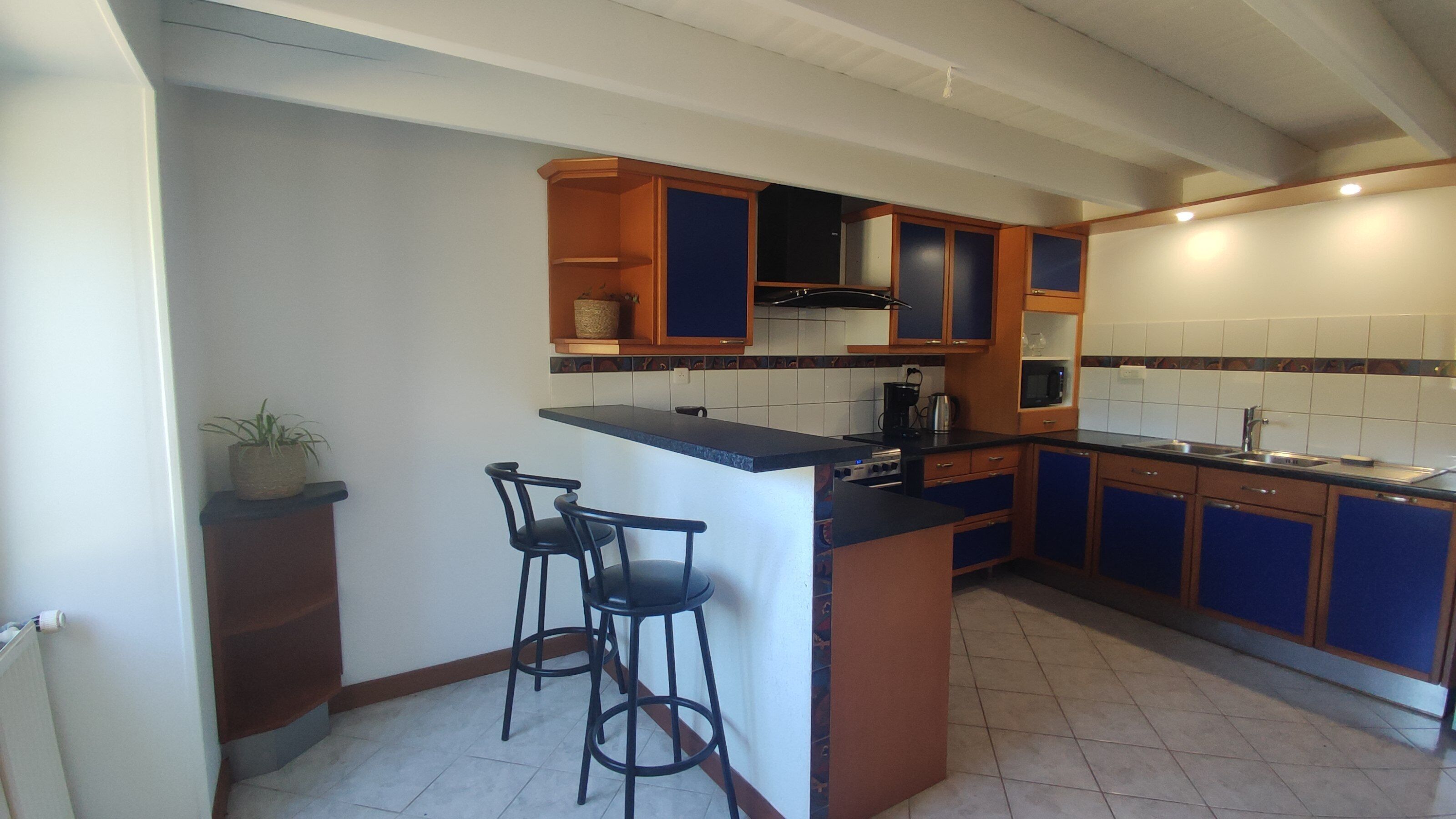 A kitchen with a central island, bar stools, wooden cabinets, and a microwave.