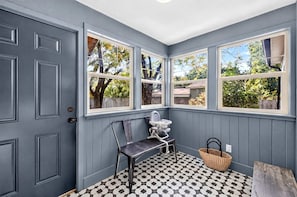 A room with a door, three windows, a chair, a baby rocker, a basket, and a patterned floor. - Cozy Getaway with Firepit, BBQ & Entertainment Room in Coeur d'Alene, Idaho (Coeur d'Alene)