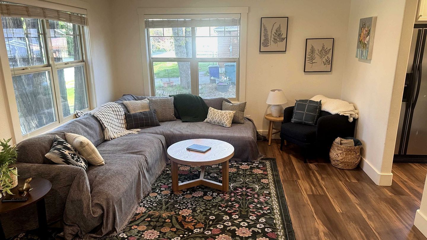 Una sala de estar con un sofá, una mesa redonda de centro, una lámpara y una alfombra.