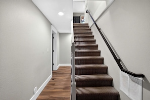 A staircase with carpeted steps and a handrail, leading to a door at the top. - Cozy Getaway with Firepit, BBQ & Entertainment Room in Coeur d'Alene, Idaho (Coeur d'Alene)