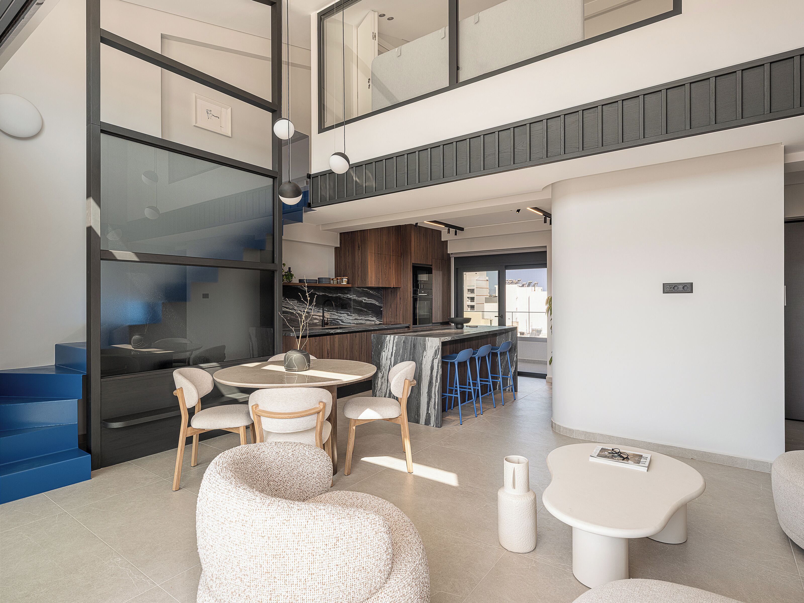 Un intérieur moderne comprenant un coin repas, une cuisine et un escalier.