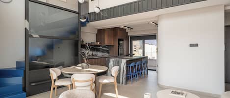 Un intérieur moderne comprenant un coin repas, une cuisine et un escalier.