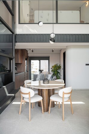 Un comedor moderno con una mesa redonda, cuatro sillas y un florero en el centro.