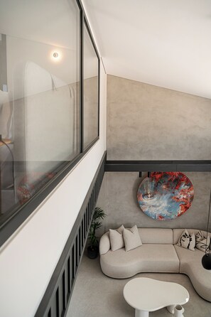 Ein modernes Interieur mit einem gebogenen Sofa, einem runden Tisch und einem großen abstrakten Gemälde.