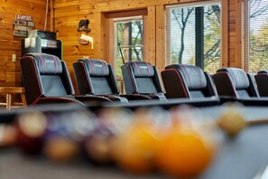 A row of black racing-style chairs with red accents in a wooden cabin setting. - Stunning Log Cabin with Movie Theatre & Hot Tub near Arts and Crafts District in Gatlinburg, TN (Gatlinburg)