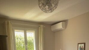 Un dormitorio con dos camas, una ventana con cortinas, un radiador y un aire acondicionado instalado en la pared.