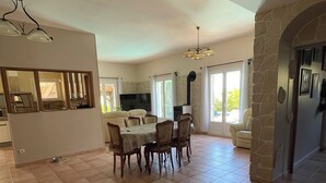 Un espacio habitable amplio con una mesa de comedor, sillas, un televisor y una pared de piedra.