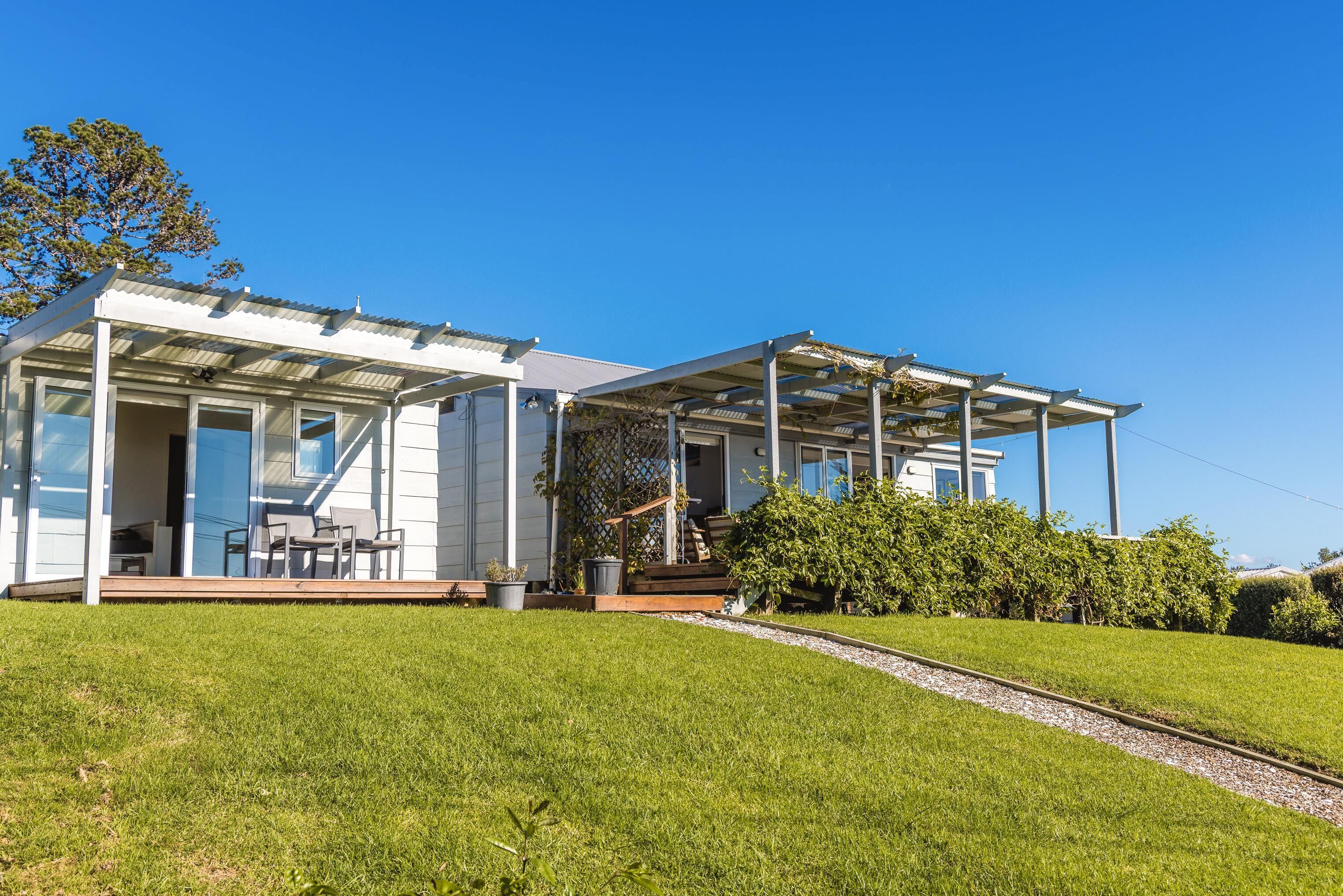 A modern house with a covered porch, a staircase, and a well-maintained lawn.