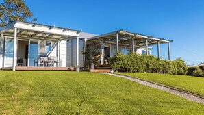 Ein modernes Haus mit überdachter Veranda, einer Treppe und einem gepflegten Rasen.