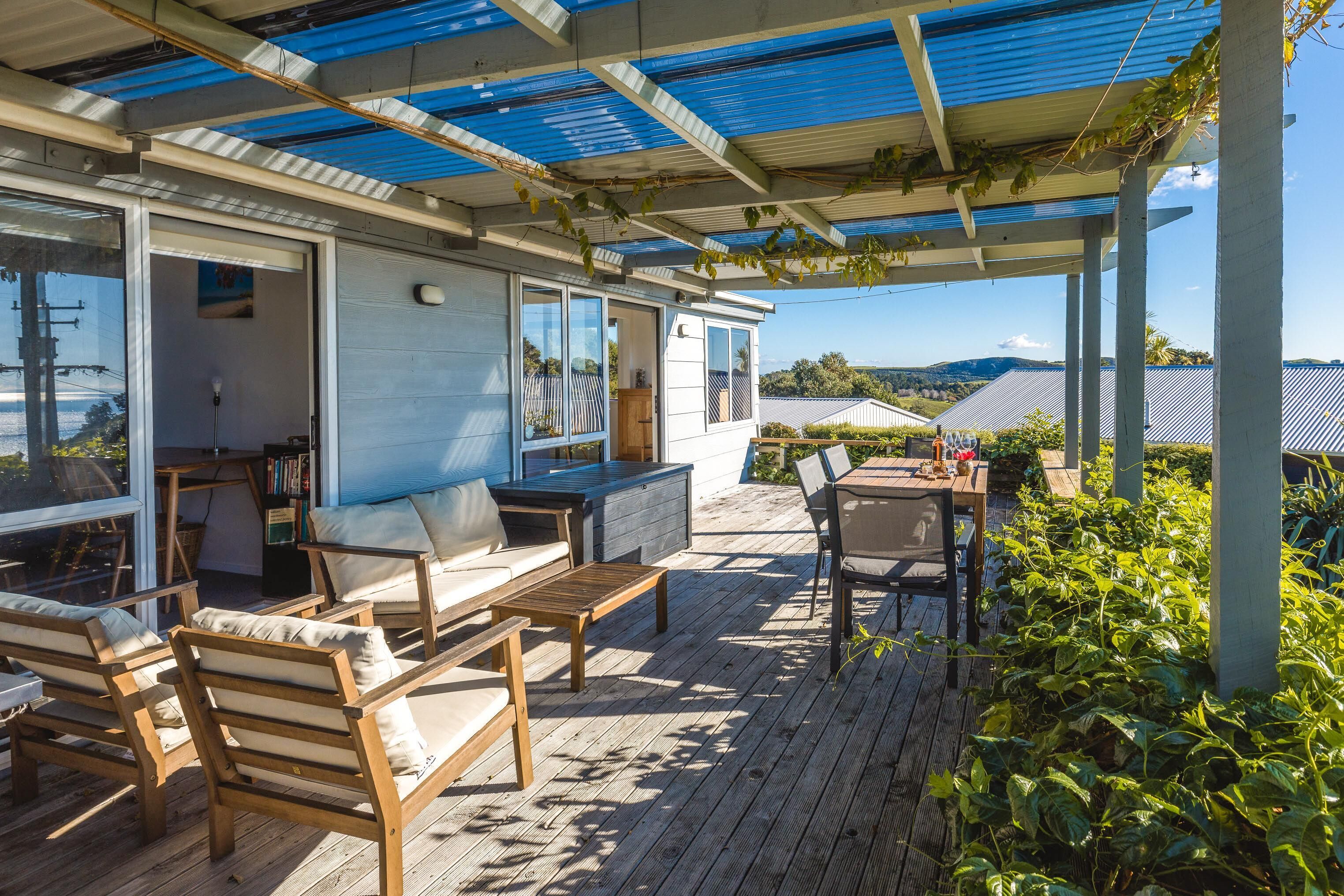 A covered outdoor deck with wooden furniture, a table, and chairs.