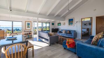 A spacious living area with a large window, a dining table, and a sofa.