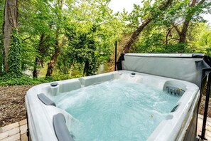 Un jacuzzi en un jardín con árboles y un camino de ladrillo.