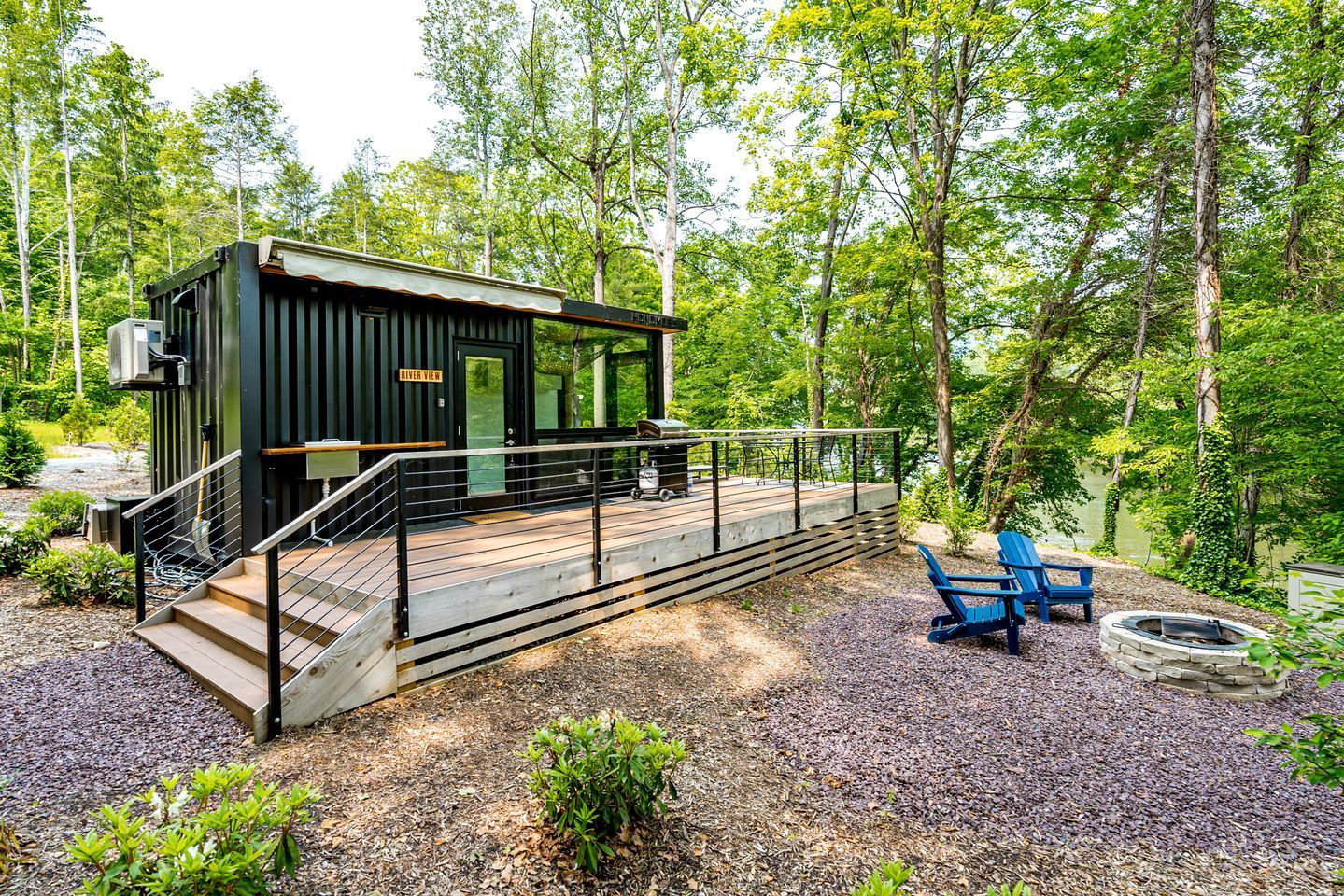 A cabin with a deck, a fire pit, and a chair.