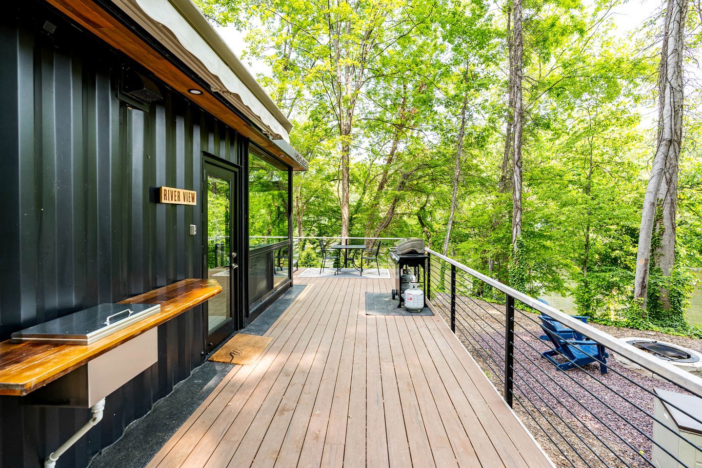 A deck with a wooden floor, a grill, and a sign reading 'RIVER VIEW'.