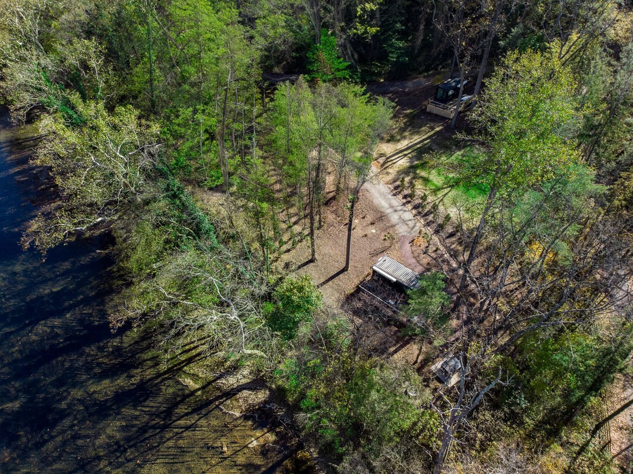An aerial view of a forested area with a dirt path leading to a small structure.