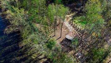 An aerial view of a forested area with a dirt path leading to a small structure.