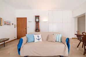 Ein Wohnzimmer mit einer Couch, einer Holztür, einer Wanduhr und einem Essbereich mit Holztisch und Stühlen.