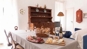 A dining table set with bread, cheese, and cured meats, accompanied by wine glasses and bottles. - Appartamento il Corsaro (Imperia)