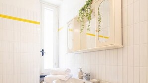 A bathroom with a white sink, a mirror, a towel rack, and a washing machine. - Appartamento il Corsaro (Imperia)