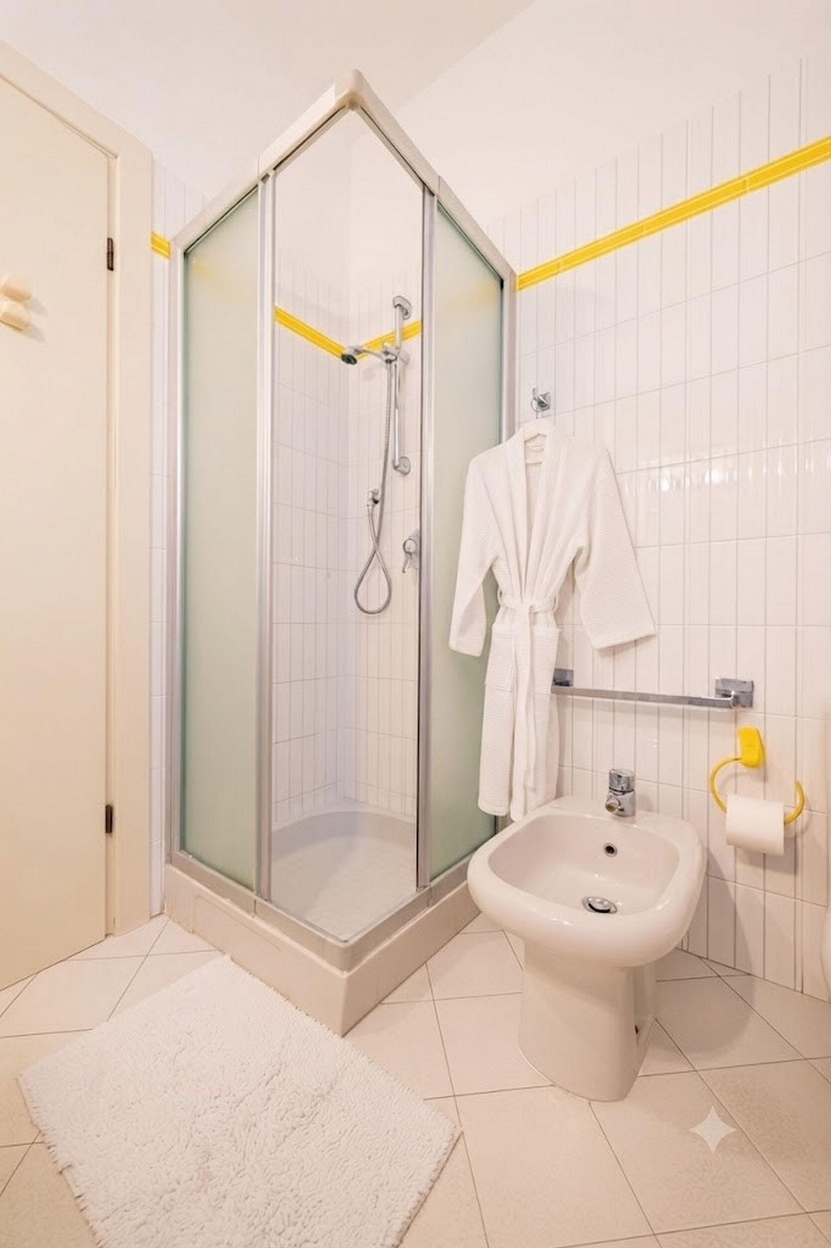 A bathroom with a glass-enclosed shower, a bidet, and a white bathtub.