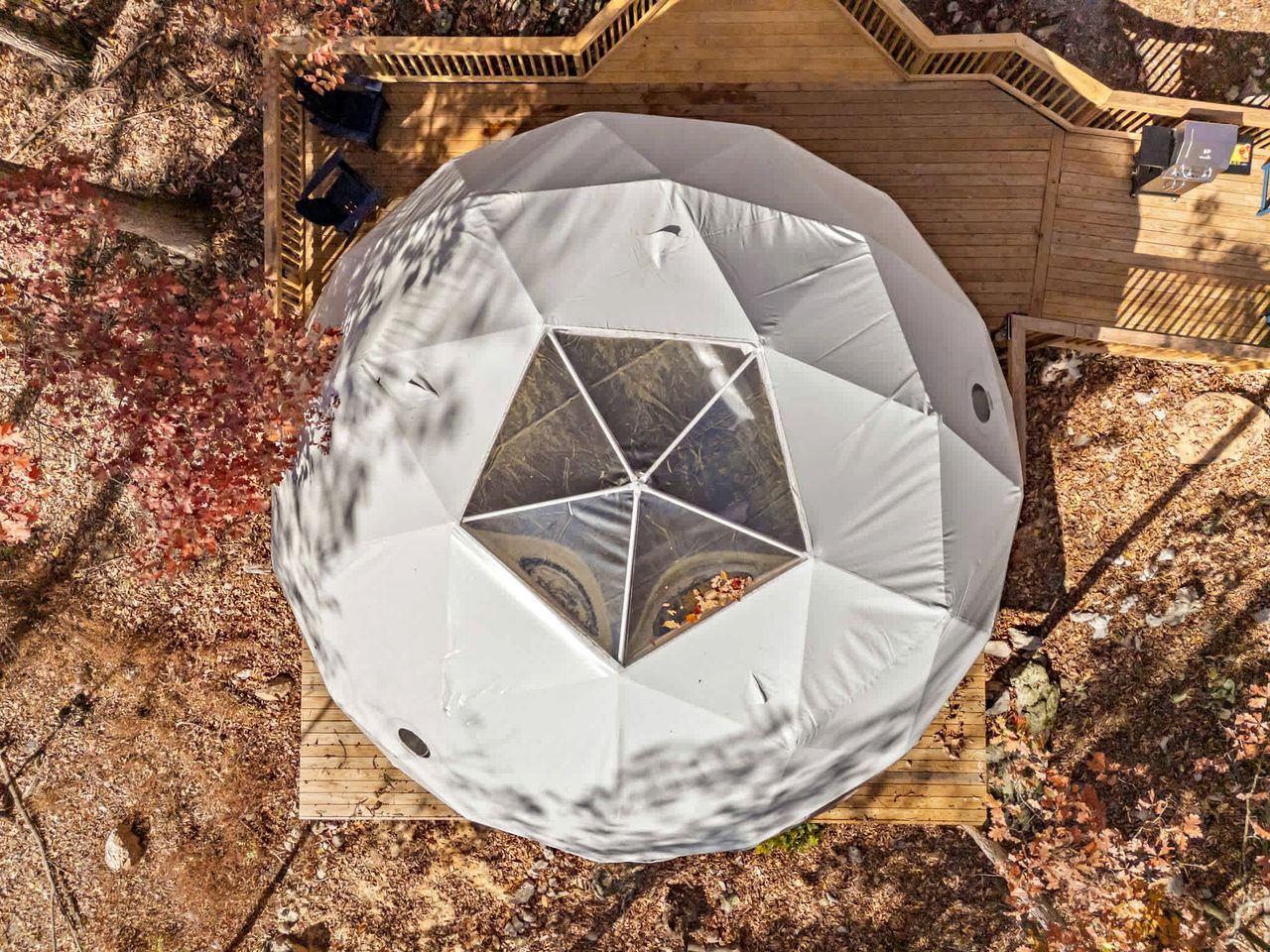 A geodesic dome structure with a wooden deck surrounding it.
