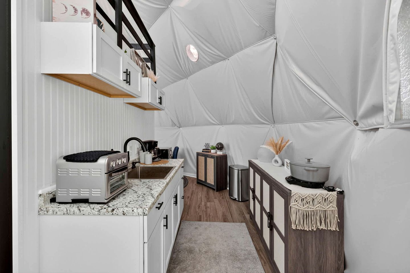 A compact kitchen with a built-in oven, a sink, and a small countertop with a coffee maker.