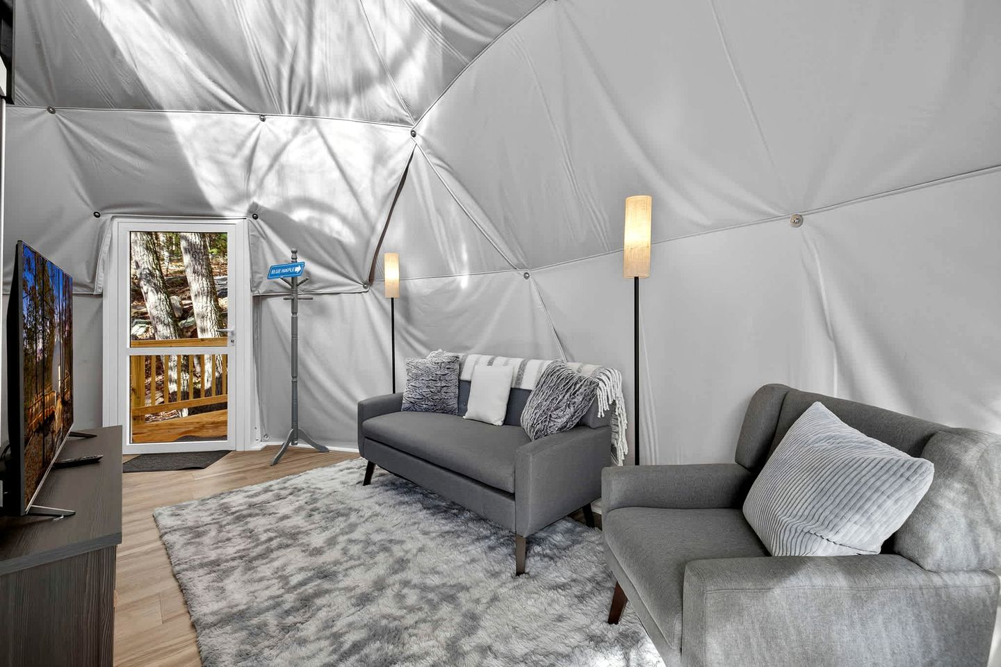A tented room with a grey sofa, a TV, and a floor lamp.