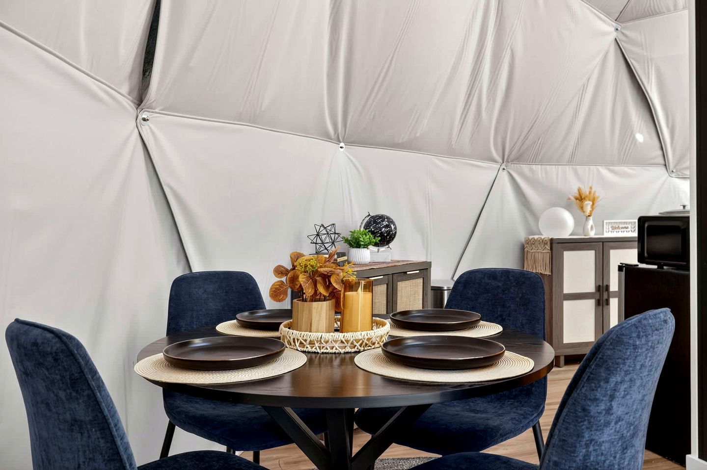 Un espace repas avec une table ronde, des chaises foncées et un élément décoratif au centre.
