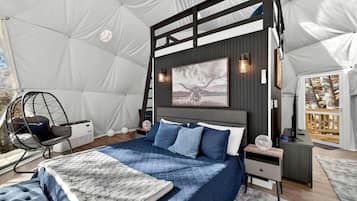 Ein Zeltraum mit Bett, Hängesessel, Schreibtisch und Wandleuchte.