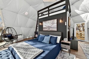 Ein Zeltraum mit Bett, Hängesessel, Schreibtisch und Wandleuchte.