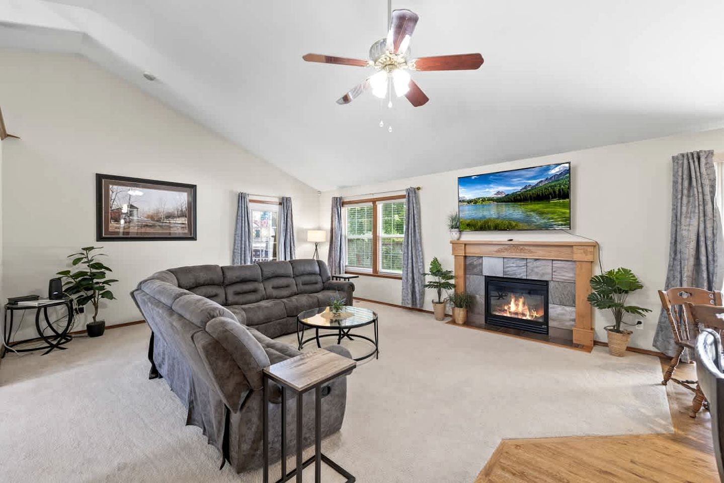 A living room with a fireplace, a sofa, a coffee table, and a ceiling fan.