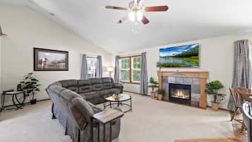 A living room with a fireplace, a sofa, a coffee table, and a ceiling fan.