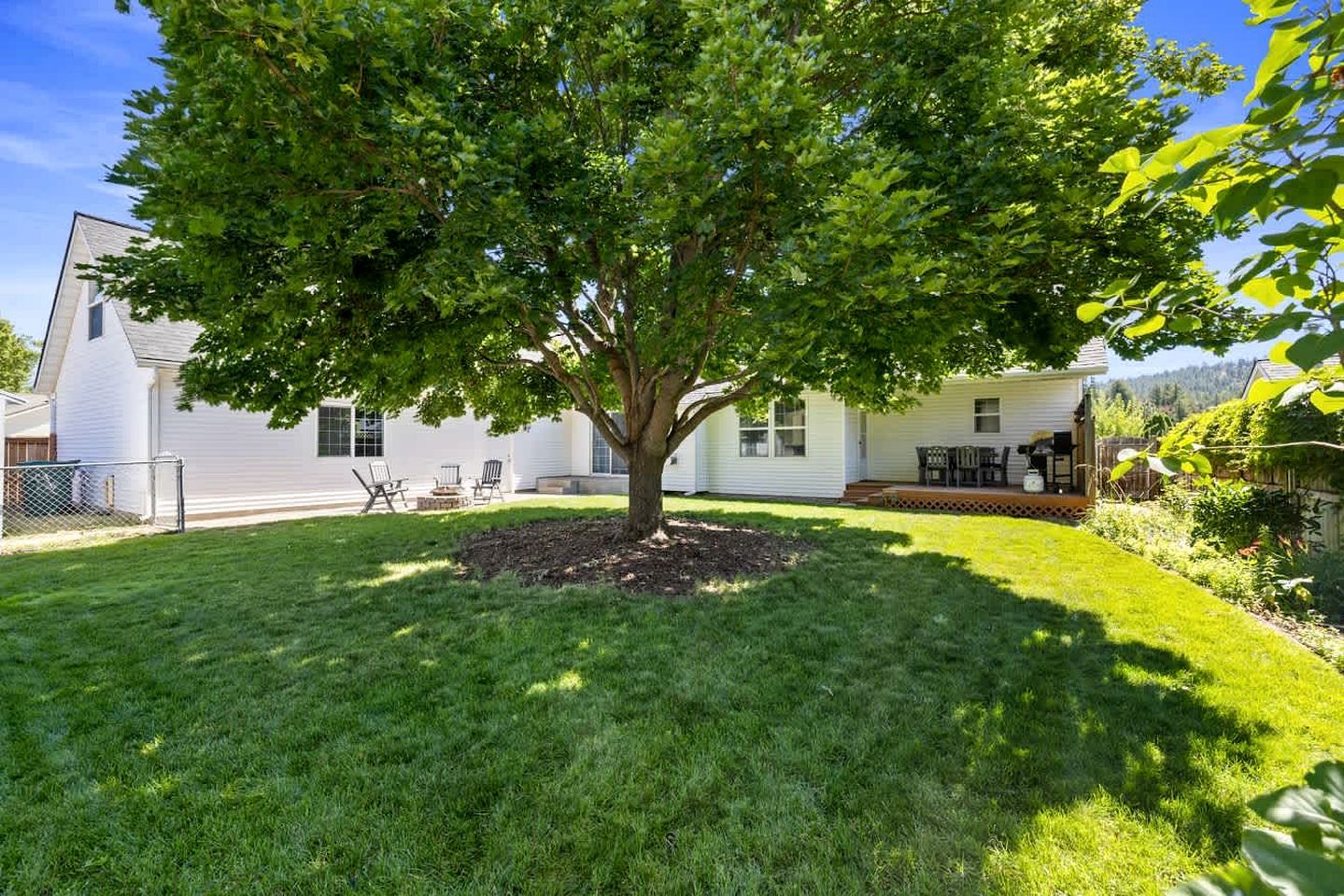 A residential property with a well-maintained lawn, a large tree, and a house with a porch.