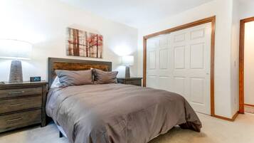 A bedroom with a bed, nightstands, a painting, and a closet.