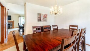 Una sala da pranzo con un tavolo e sedie in legno, un lampadario e un camino sullo sfondo.