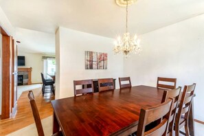 Ein Esszimmer mit Holztisch und Stühlen, einer Kristallleuchter und einem Kamin im Hintergrund.