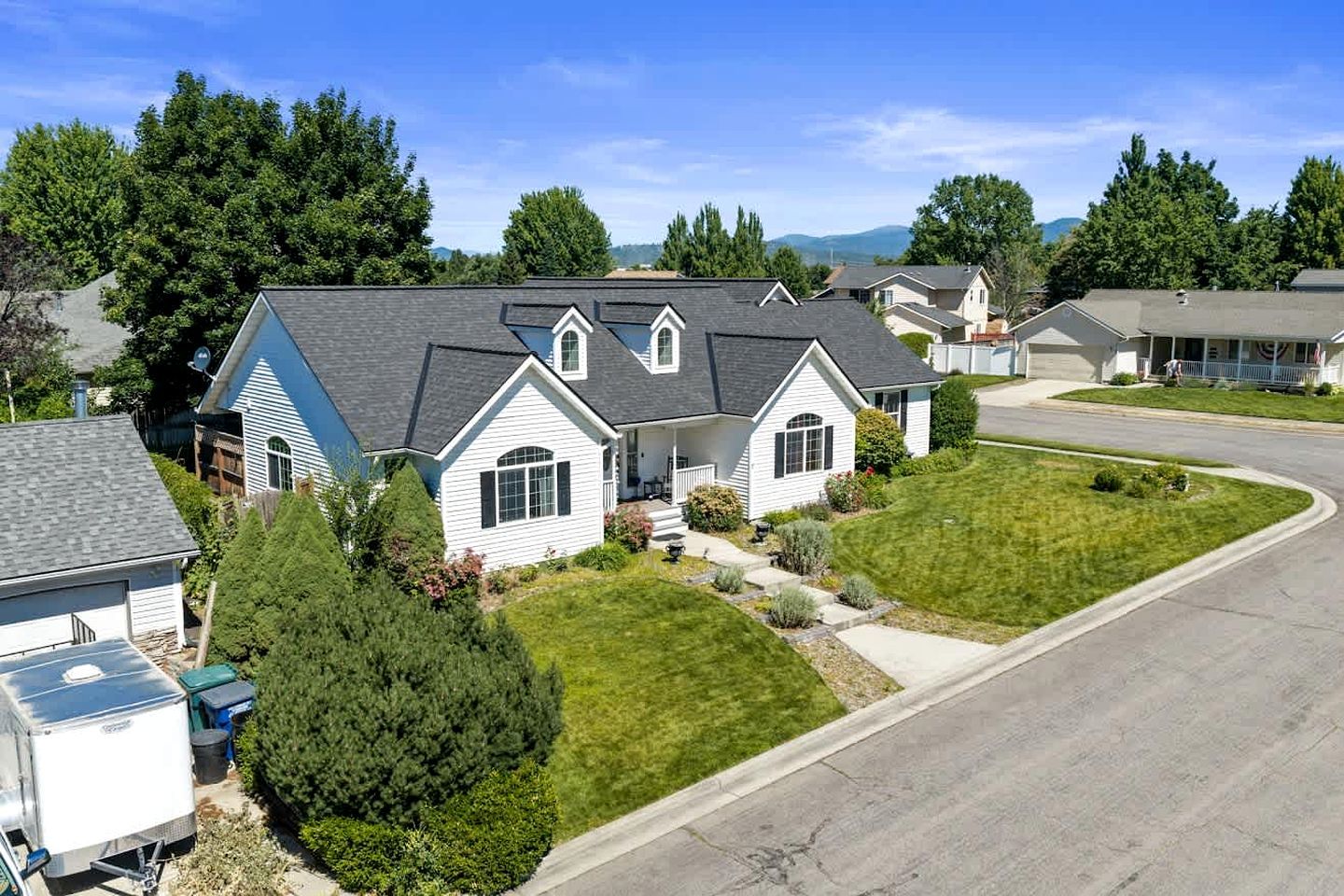 A residential house with a sloped roof, a front porch, and a well-maintained lawn.