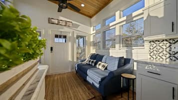 A modern kitchen with white cabinets, a blue sofa, and a ceiling fan.