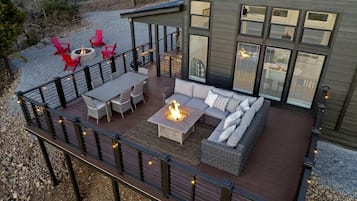 Een terras met tuinmeubilair, een vuurkuil en een modern gebouw met grote ramen.