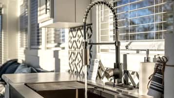 A modern kitchen with a stainless steel sink, a flexible faucet, and a window with blinds.
