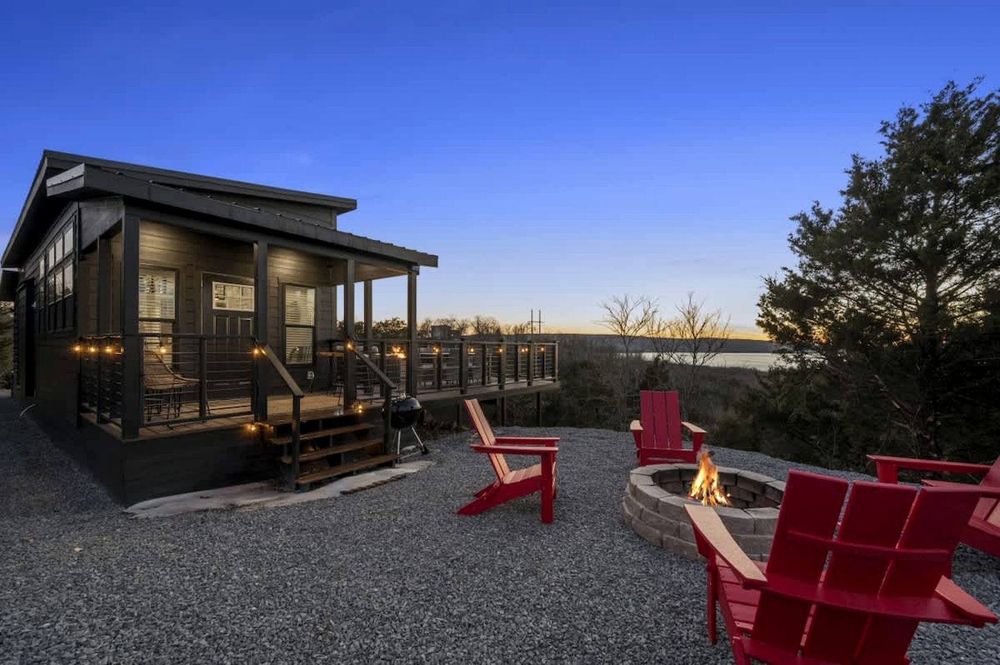 A cabin with a deck, outdoor seating, and a fire pit.