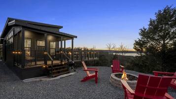 A cabin with a deck, outdoor seating, and a fire pit.