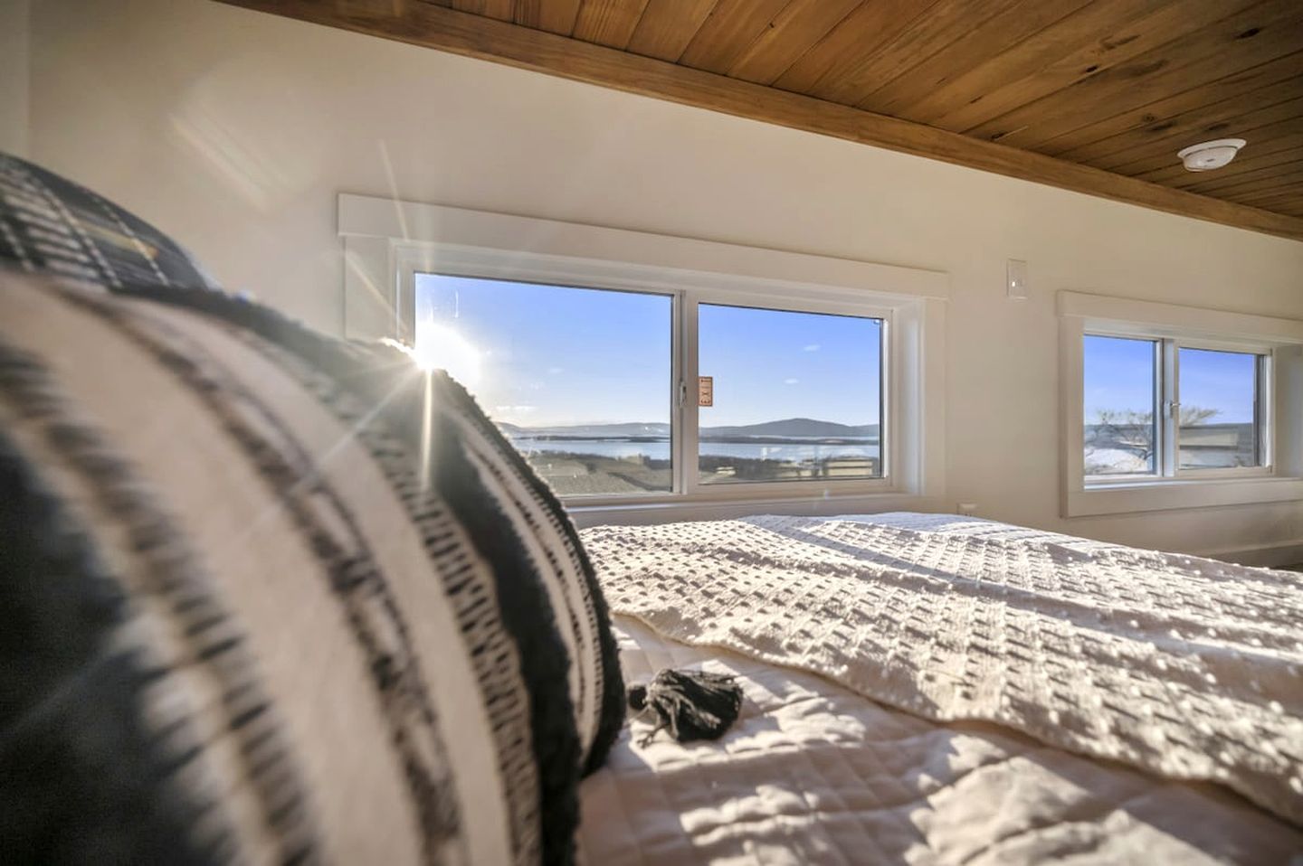A bedroom with a large bed, a window with a view of the outdoors, and a ceiling with wooden beams.